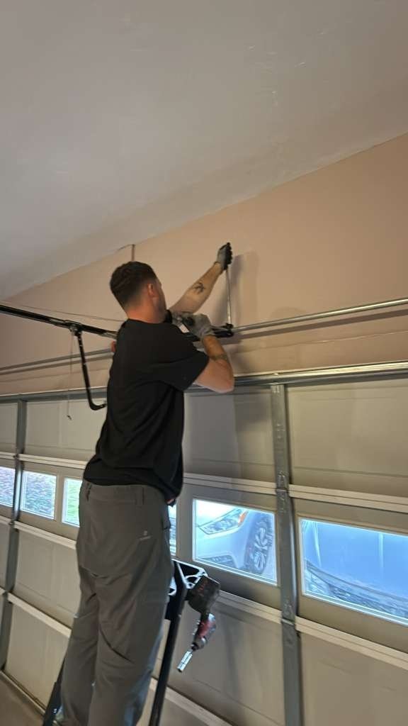 Technician working at the header of a garage door that has window panels