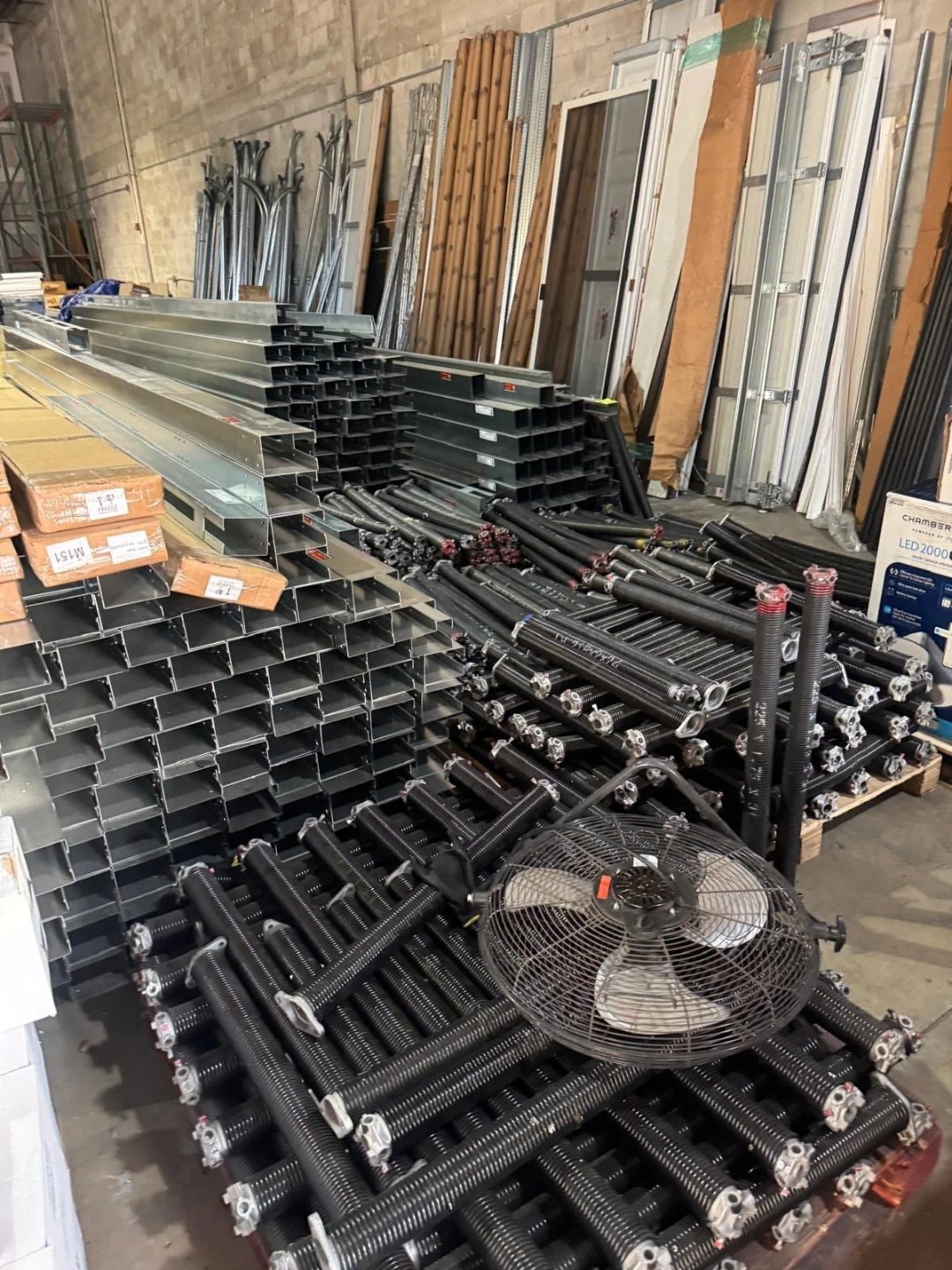 Stacks of steel garage door track and parts on warehouse racks